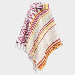 Colorful yellow and red patterned poncho with fringes on a light gray background