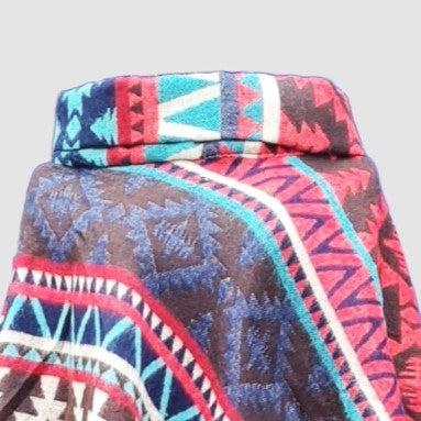 Colorful patterned roll neck poncho with an Aztec design on a light gray background