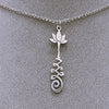 Silver necklace with a lotus flower and a Unalome design.