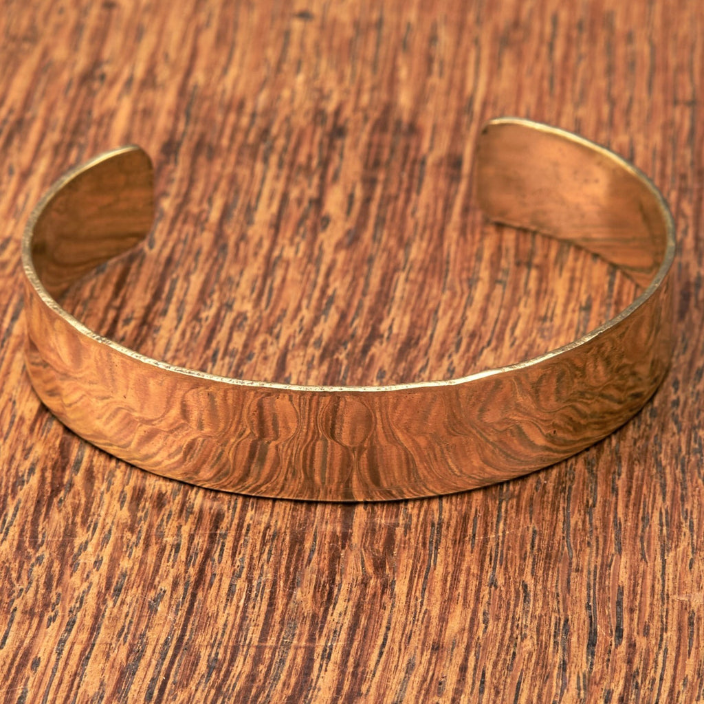 An adjustable, hammered, dimpled textured pure brass simple cuff bracelet designed by OMishka.