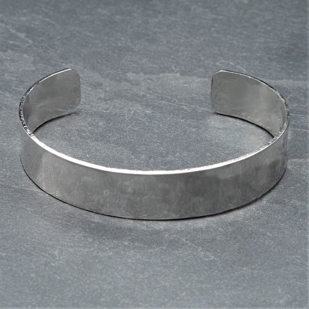 An adjustable, hammered dimpled textured silver simple cuff bracelet designed by OMishka.