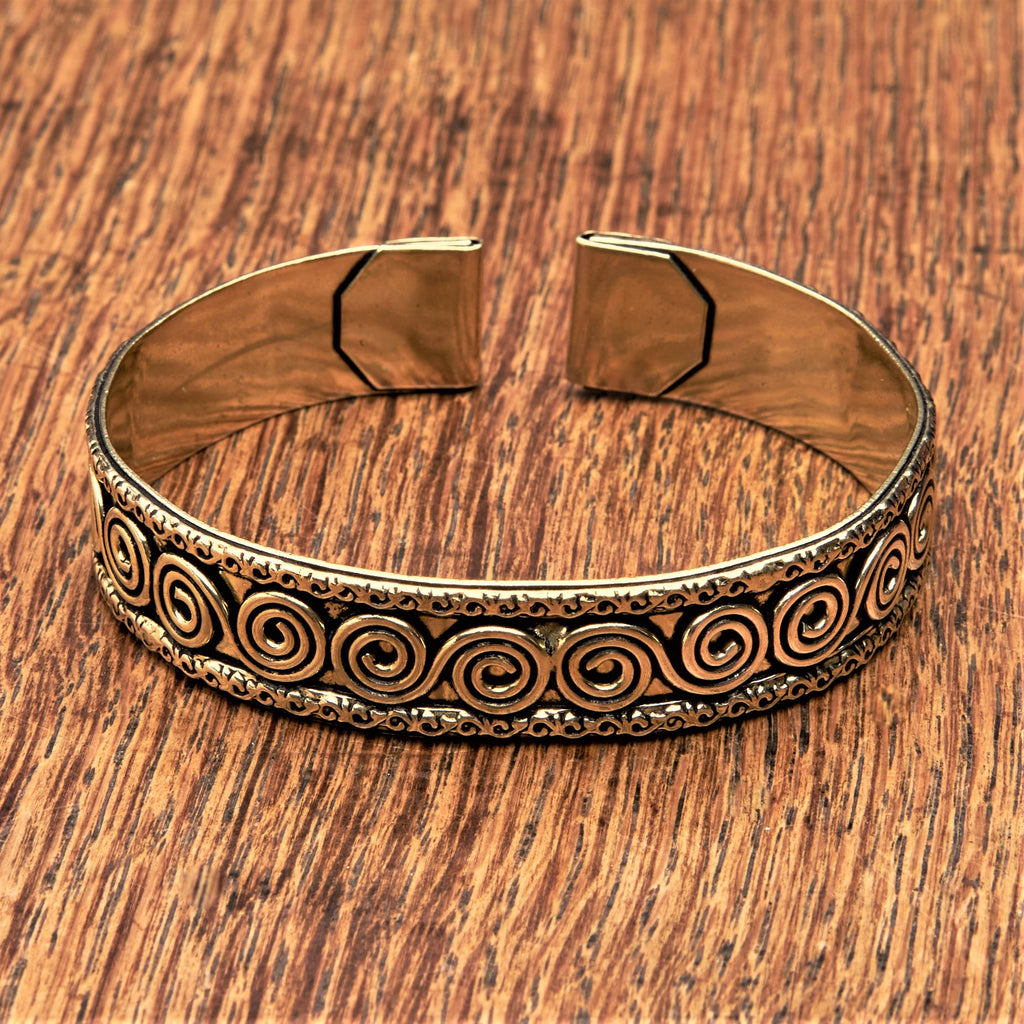 An adjustable, handmade pure brass spiral patterned cuff bracelet designed by OMishka.