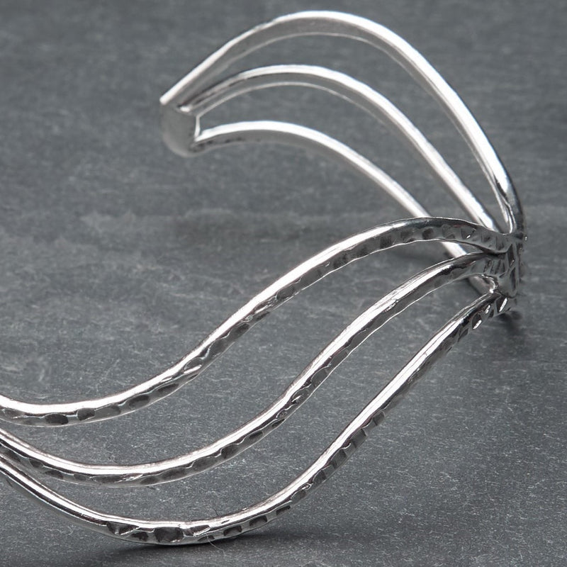 An adjustable, hammered silver triple wave cuff bracelet designed by OMishka.