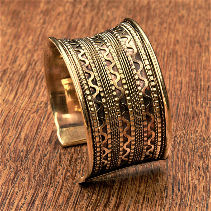 An adjustable, wide concave shaped pure brass wavy patterned cuff bracelet designed by OMishka.