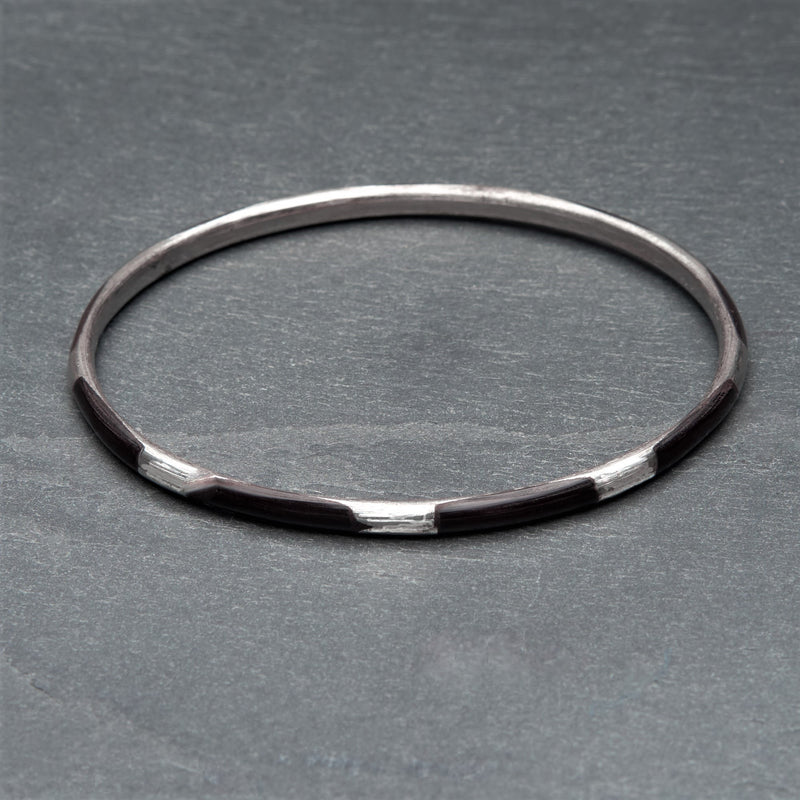 An artisan handmade, silver and black enamel striped thin bangle bracelet designed by OMishka.