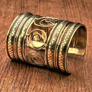 An artisan handmade extra wide, pure brass, open spiral patterned cuff bracelet designed by OMishka.