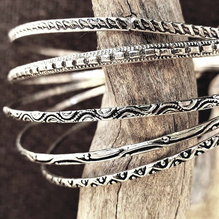 An artisan handmade, silver set of 5 bangle bracelets each etched with traditional Indian patterns designed by OMishka.