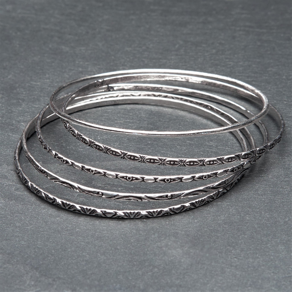 An artisan handmade, silver set of 5 thin bangles each etched with traditional Indian patterns designed by OMishka.
