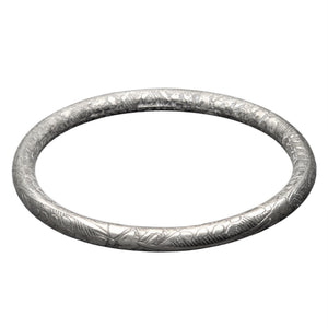 An artisan handmade, light, silver floral etched bangle bracelet designed by OMishka.