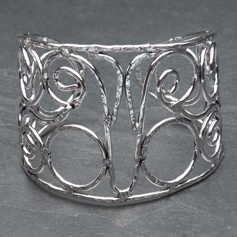 An artisan handmade, wide silver swirl patterned cuff designed by OMishka.