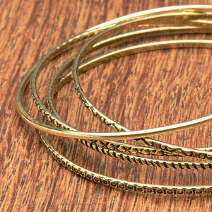 A handmade, pure brass set of 5 thin bangle bracelets each etched with traditional Indian patterns designed by OMishka.