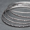An artisan handmade, silver set of 5 bangles each etched with traditional Indian patterns designed by OMishka.