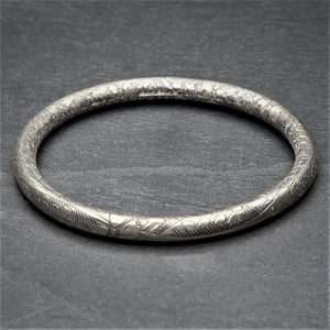 A handmade, light, silver floral etched bangle bracelet designed by OMishka.