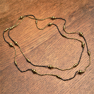 Handmade and nickel free, golden and black brass, striped beaded, long single strand necklace designed by OMishka.