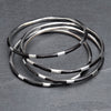 A silver and black enamel striped, set of 4 thin bangle bracelets designed by OMishka.