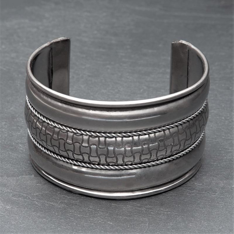 An adjustable wide silver striped, geometric patterned cuff bracelet designed by OMishka.